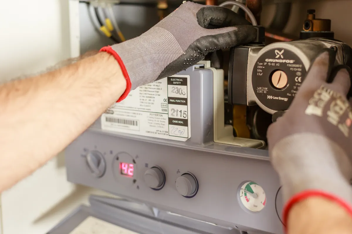 A gloved technician adjusting heating-system controls
