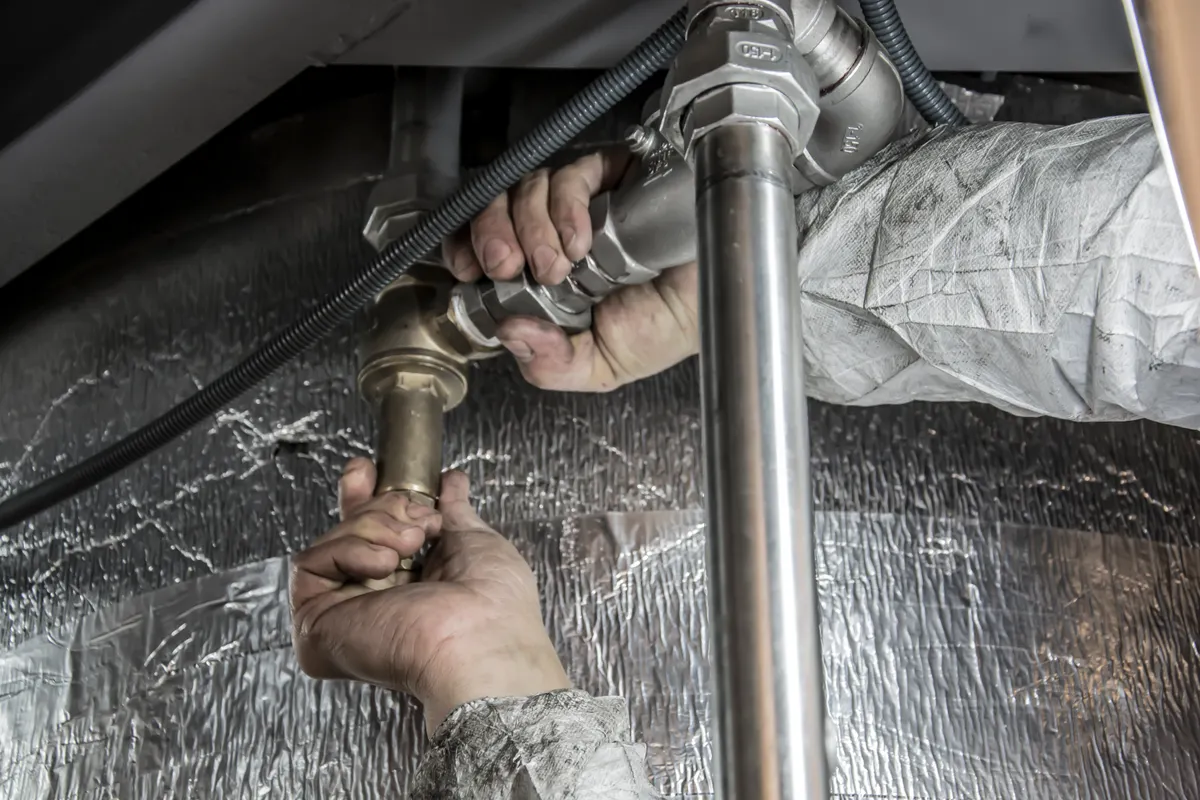 A plumber tightening a metal pipe fitting