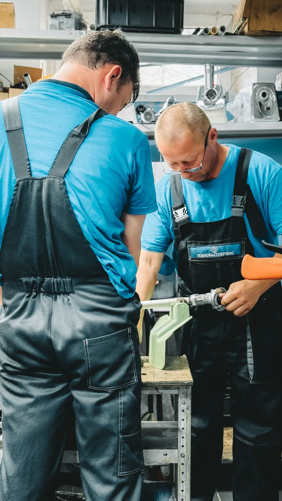 Two technicians in matching workwear collaborating on a plumbing fitting